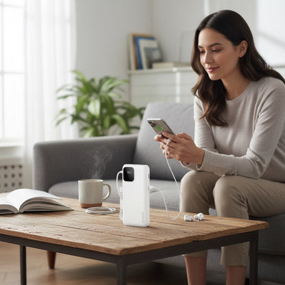 Batterie externe Levko 10000mAh blanche avec câbles intégrés et écran numérique utilisée par une femme sur un canapé